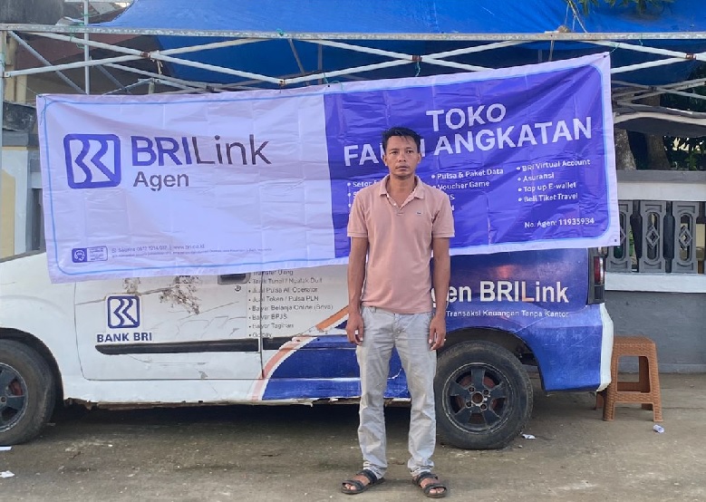 Fauzi bersama Kios BRILink miliknya.